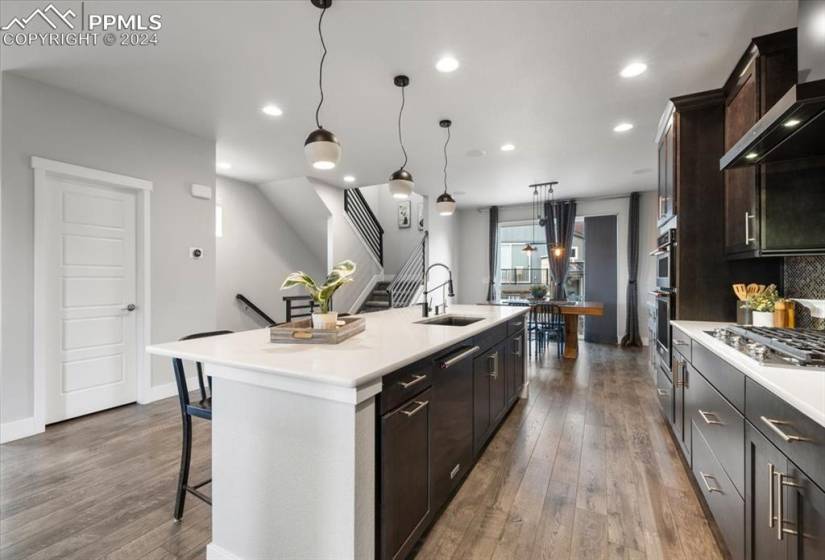 Kitchen with appliances with stainless steel finishes, a kitchen island with sink, a breakfast bar area, and wood-type flooring