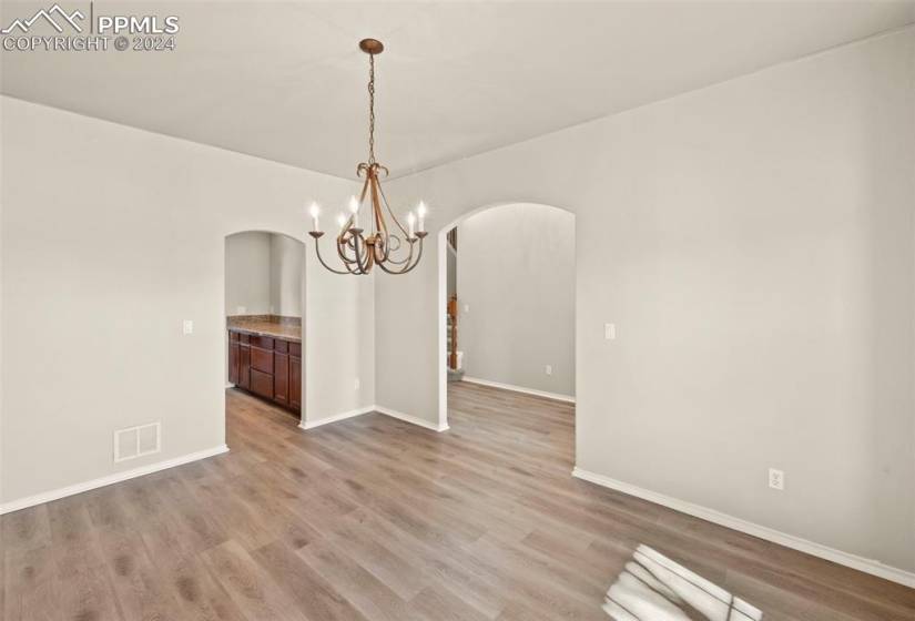 Empty room with an inviting chandelier and light hardwood / wood-style flooring