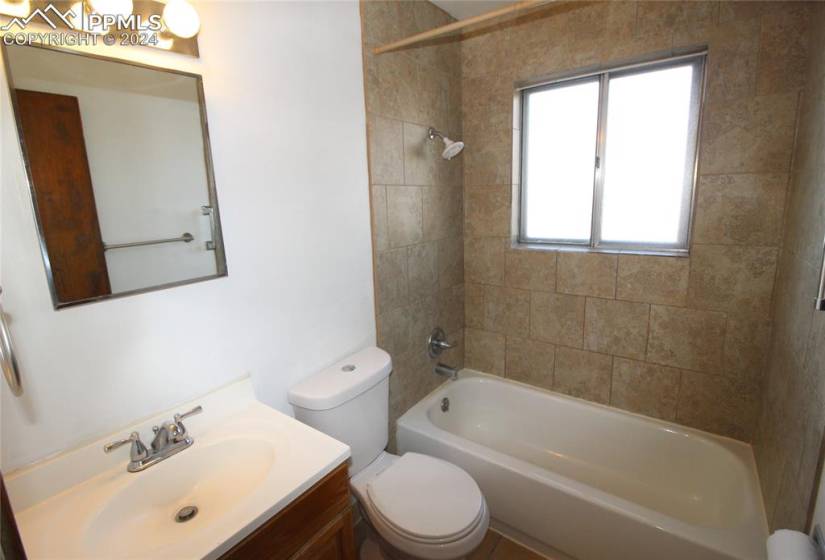 Full bathroom featuring tiled shower / bath, toilet, and vanity