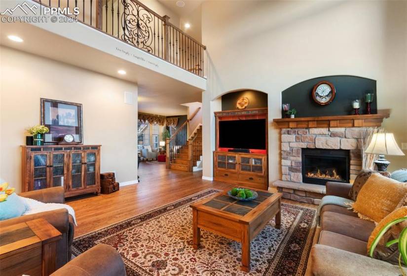 Living room with a towering ceiling, hardwood / wood-style flooring, and a fireplace