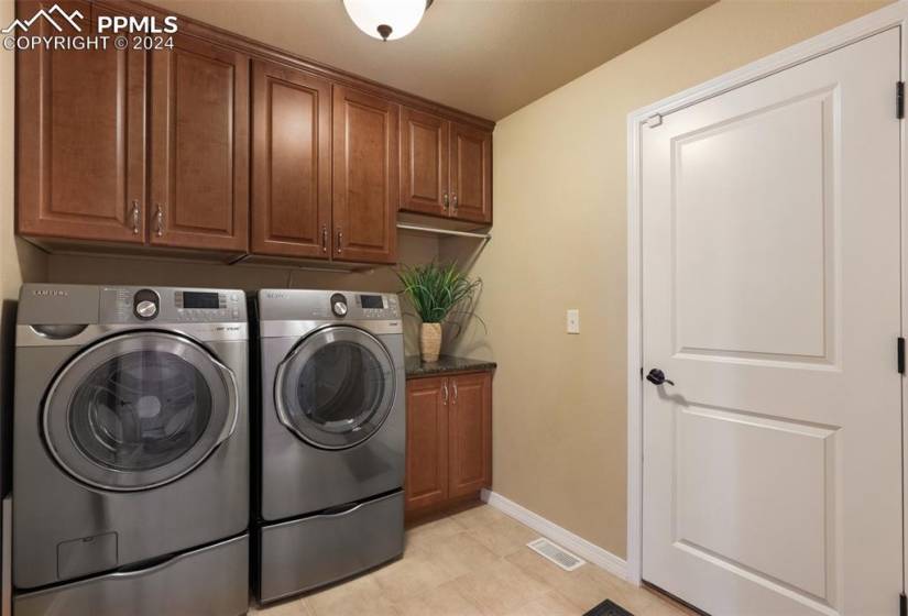 Main level Laundry room featuring cabinets, independent washer and dryer, and light tile flooring