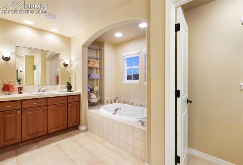 Bathroom featuring vanity, tile flooring, and tiled tub