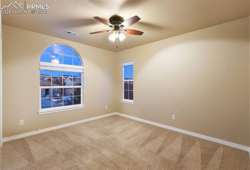 Carpeted room with ceiling fan and 2 windows