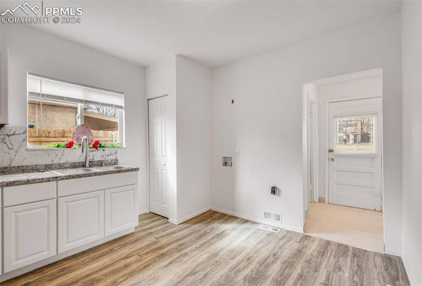 Kitchen featuring backsplash, stone counters, white cabinets, light hardwood / wood-style floors, and sink