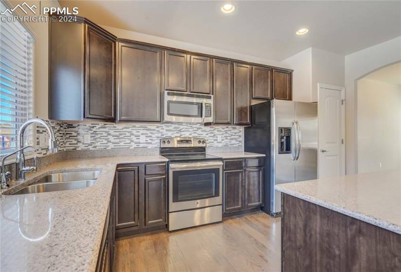 Kitchen Features Engineered Hardwood Floors | Stainless Steel Appliances | Slab Granite Countertops | 42” Upper Cabinetry w/Crown Molding | Dual Basin Undermount Sink | Tile Backsplash | Center Island w/Ample Prep Space + Room for Seating | Pantry | Walkout to Rear Patio | Opens to Family Room