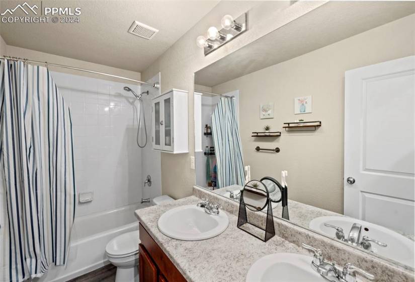 Full bathroom with dual sinks, shower / bath combo