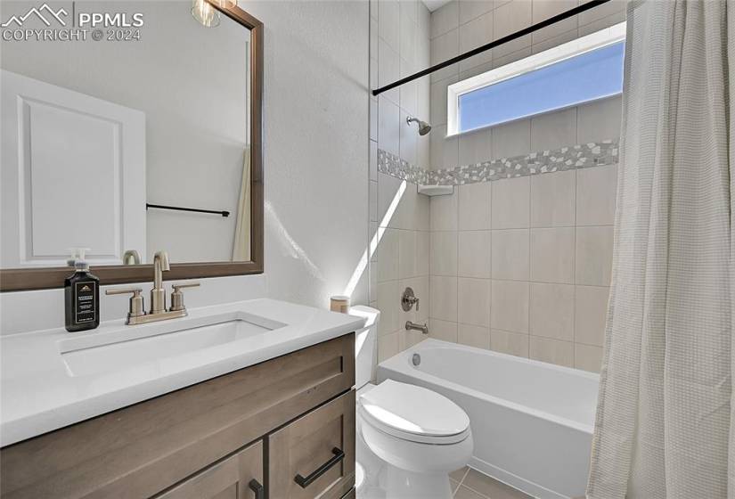 Full bathroom with toilet, tile floors, shower / bath combo with shower curtain, and vanity