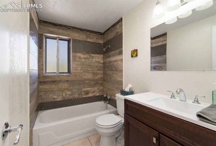 Full bathroom featuring vanity with extensive cabinet space, tiled shower / bath, toilet, and tile flooring