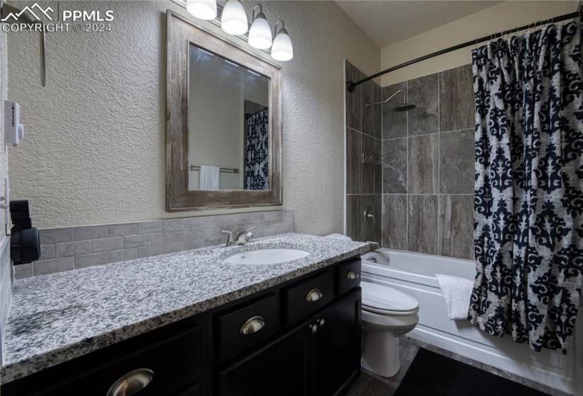 Full Hall Bathroom with extended vanity, framed mirror, and tiled tub/shower