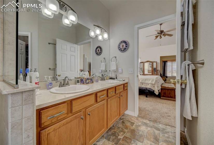 Bathroom featuring tile floors, double sink, vanity with extensive cabinet space, and ceiling fan