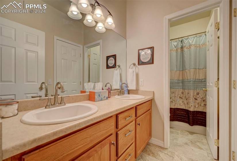 Bathroom featuring tile floors, an inviting chandelier, double sink, and large vanity
