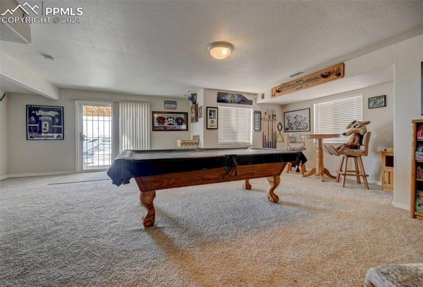 Recreation room with a textured ceiling, light colored carpet, and pool table