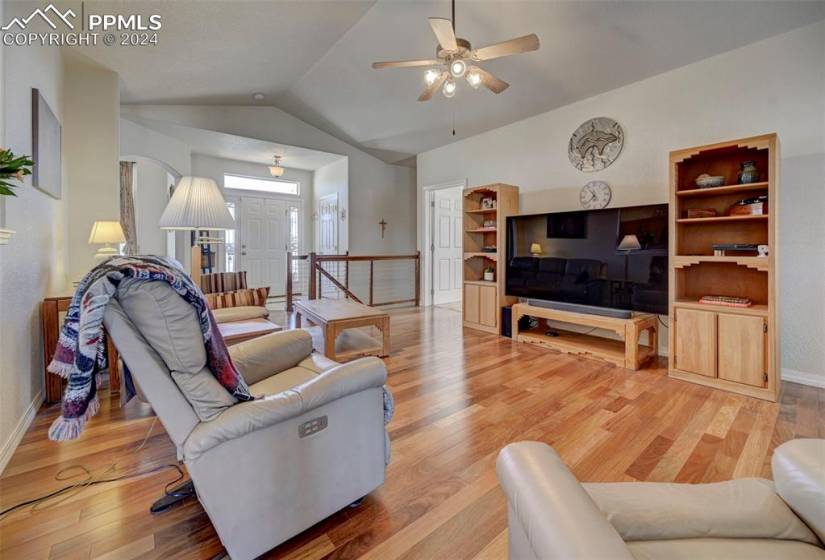 Living room featuring light hardwood / wood-style flooring, vaulted ceiling, and ceiling fan