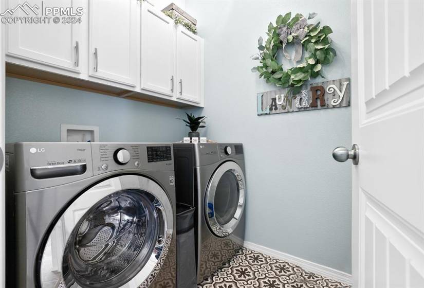 Laundry area featuring cabinets, washing machine and clothes dryer, light tile floors, and hookup for a washing machine