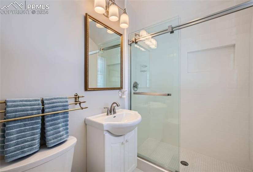 Bathroom featuring walk in shower, vanity, and toilet