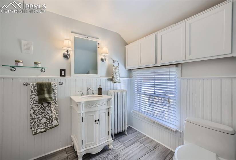 Bathroom with vanity, tile flooring, toilet, vaulted ceiling, and radiator heating unit