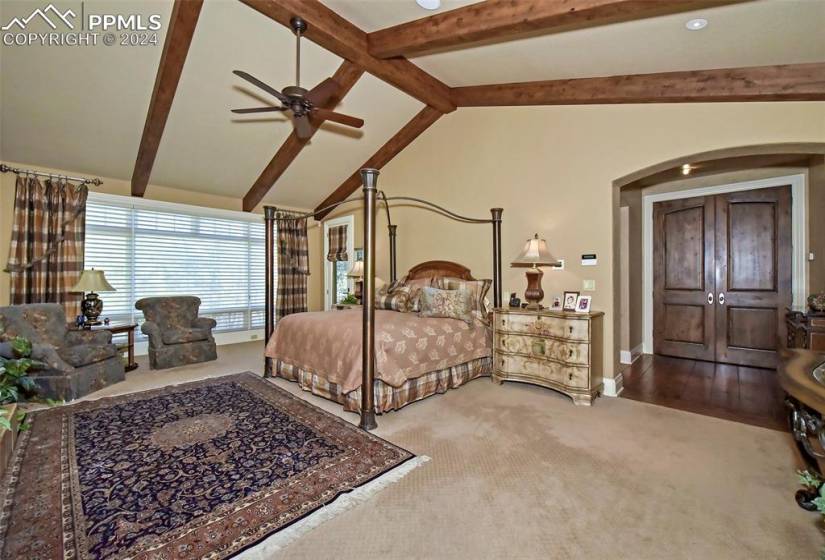 Bedroom featuring carpet floors, ceiling fan, and vaulted ceiling with beams