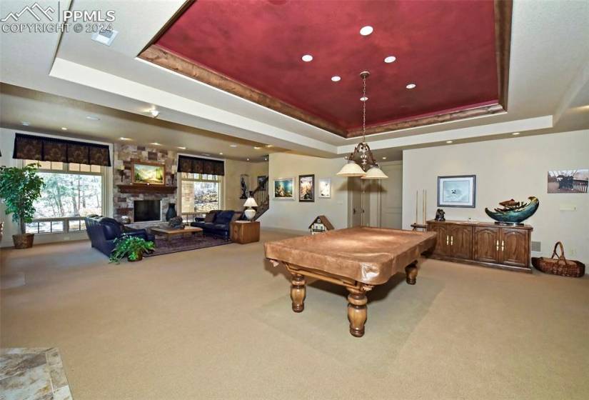 Game room featuring a tray ceiling, a fireplace, light colored carpet, and billiards