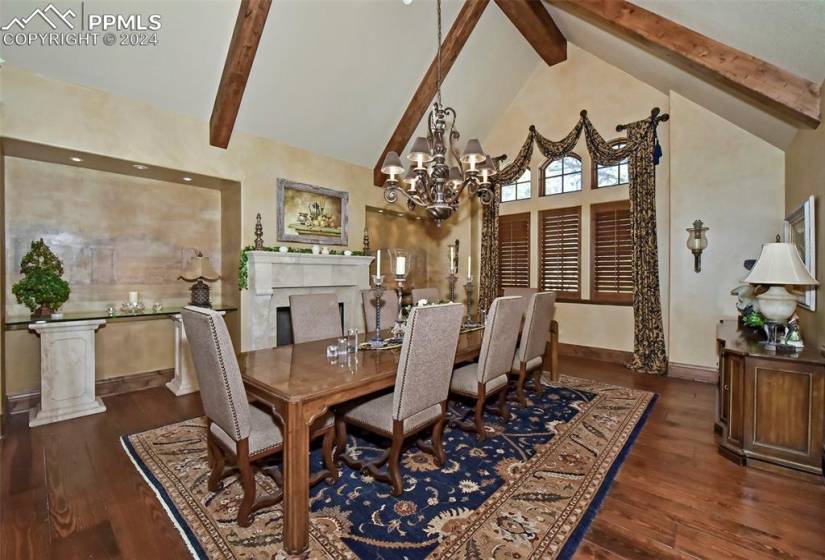 Dining area with high vaulted ceiling, beam ceiling, a chandelier, and dark hardwood / wood-style flooring