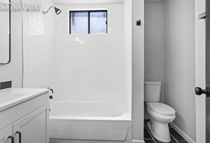 Full bathroom featuring toilet, vanity, tiled shower / bath, and tile flooring