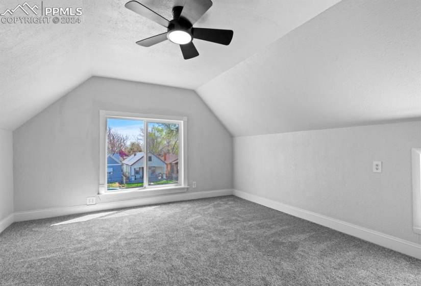 Additional living space with ceiling fan, carpet floors, vaulted ceiling, and a textured ceiling