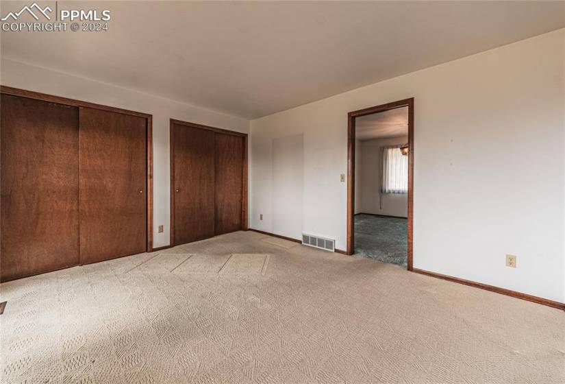 Unfurnished second bedroom or office with light colored carpet and two closets