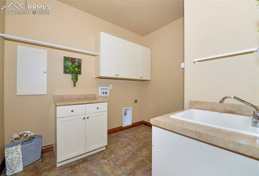 Laundry area featuring cabinets, tile floors, electric dryer hookup, sink, and washer hookup