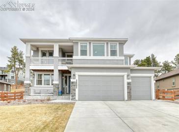 View of front of house featuring a front lawn, a balcony, and a garage