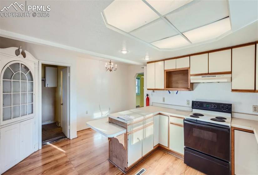Kitchen featuring an inviting chandelier, light hardwood / wood-style flooring, electric stove, and kitchen peninsula
