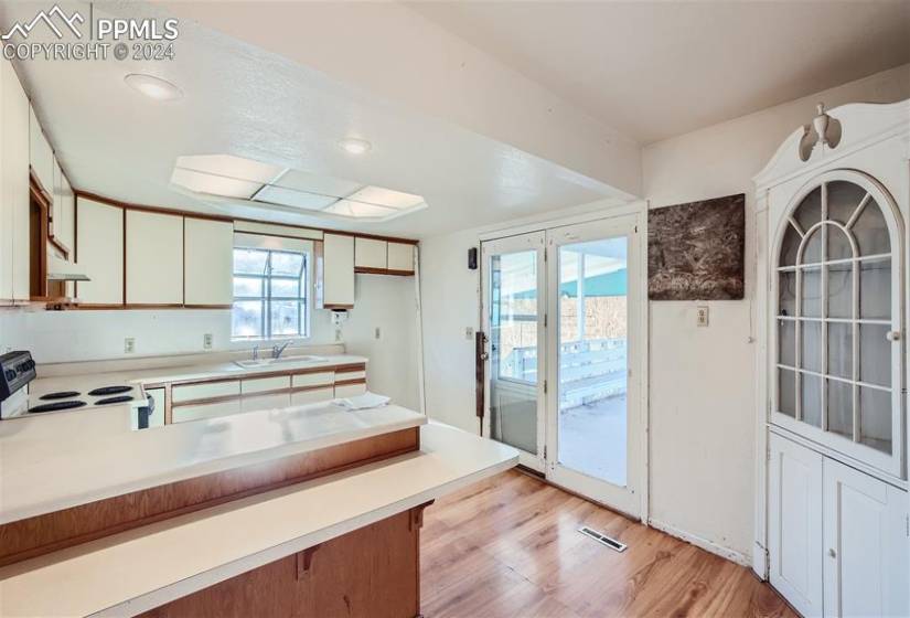 Kitchen with white cabinets, light hardwood / wood-style flooring, sink, white electric range, and wall chimney range hood