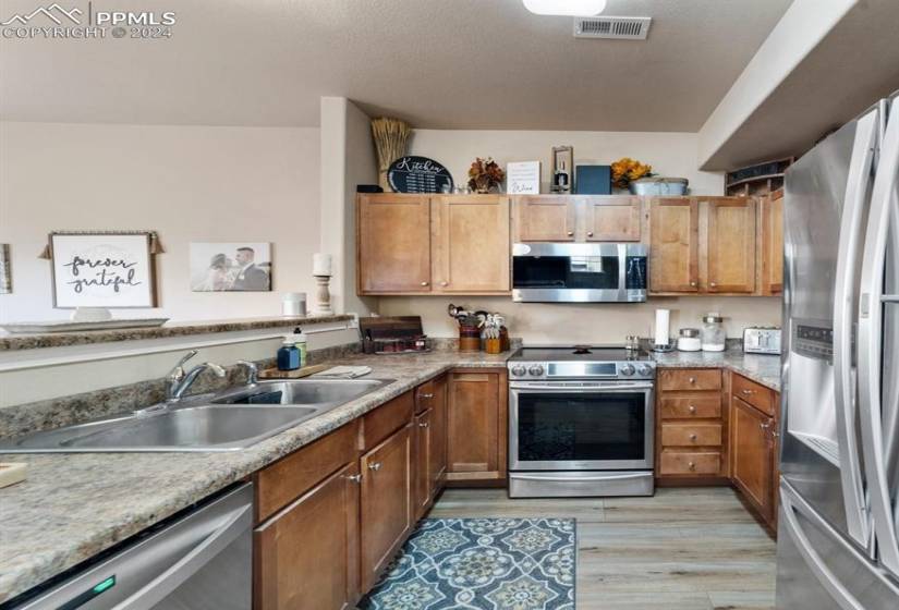 Kitchen featuring stainless steel appliances, light hardwood / wood-style flooring, and sink