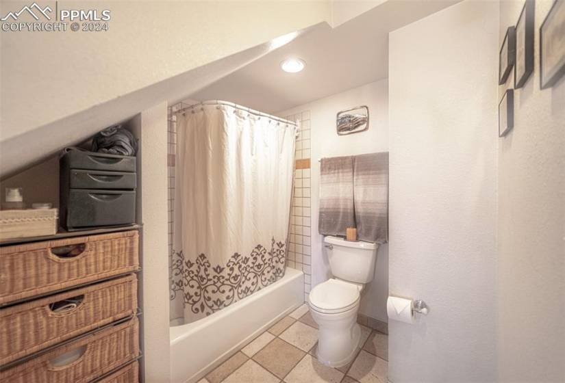 Bathroom featuring shower / tub combo with curtain, toilet, and tile floors