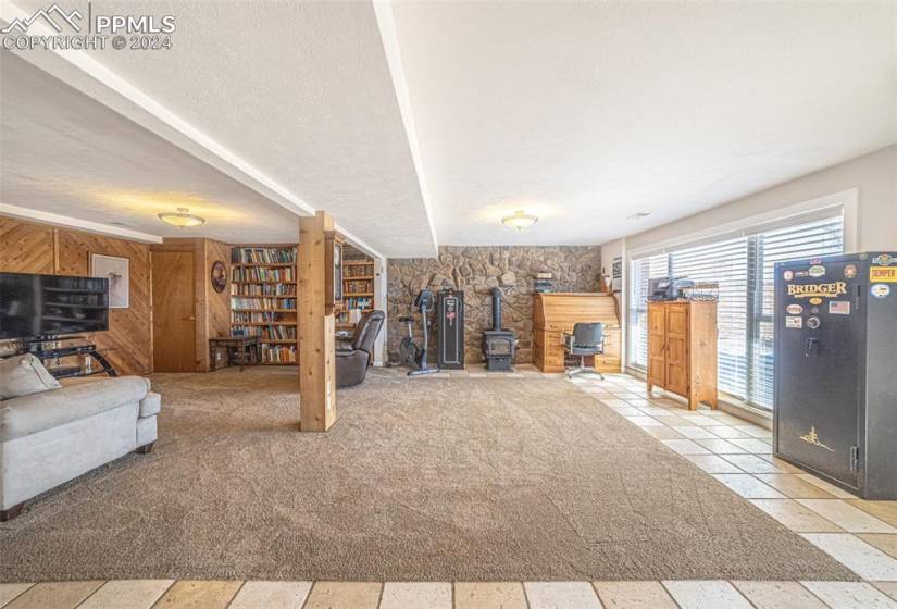 Unfurnished living room featuring light carpet, wooden walls, a wood stove, and a textured ceiling