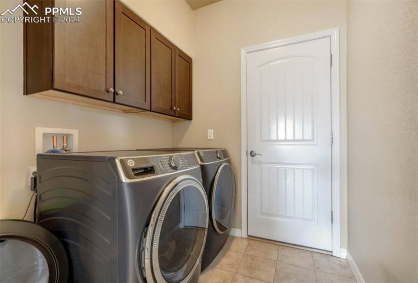 Main level laundry room has built-in cabinets for storage, and leads to the 3 car garage.