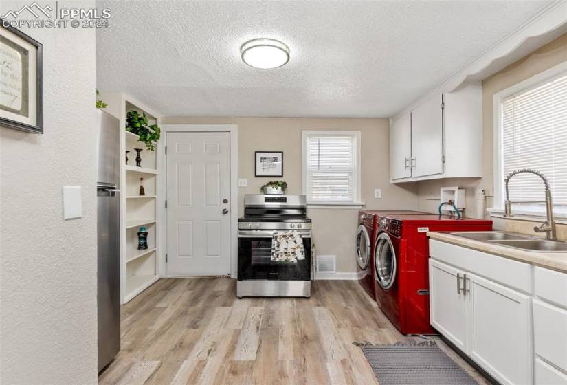 Kitchen featuring sink, white cabinetry, separate washer and dryer, and stainless steel range
