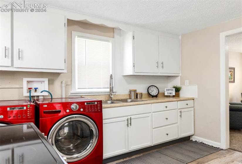Laundry room featuring cabinets, separate washer and dryer, a textured ceiling, sink, and dark hardwood / wood-style flooring