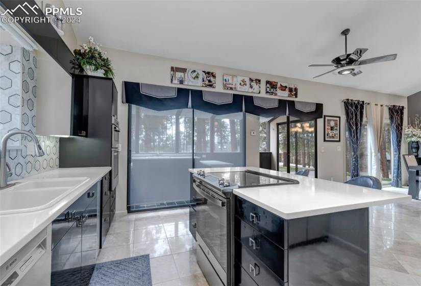 Kitchen featuring light tile floors, stainless steel appliances, sink, a center island, and ceiling fan