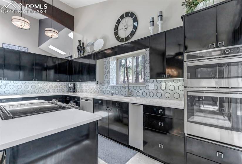 Kitchen featuring sink, stainless steel appliances, decorative light fixtures, and backsplash