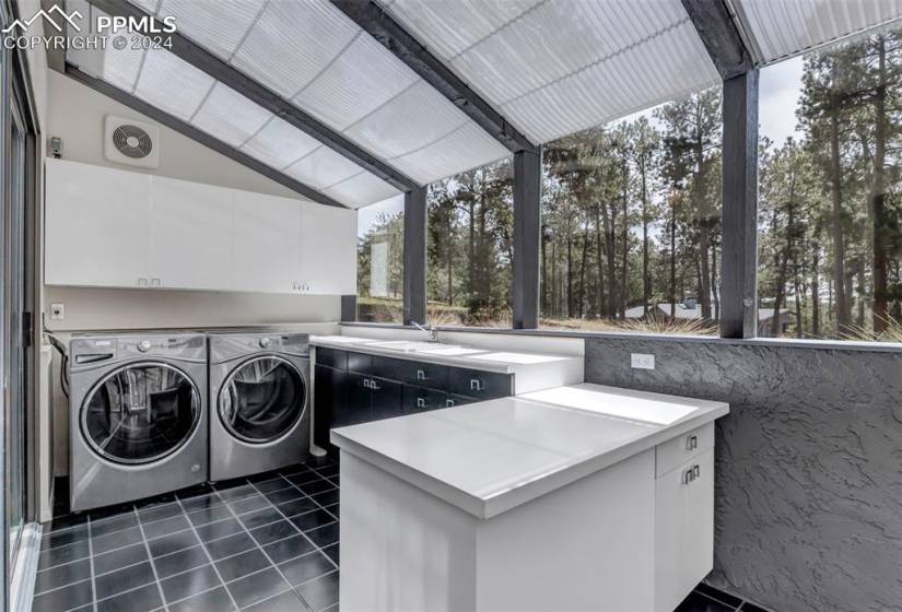 Laundry area featuring washing machine and clothes dryer, sink, cabinets, and dark tile floors