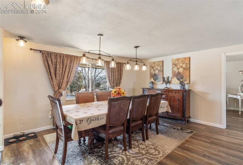 Dining area with an inviting chandelier, dark wood laminate flooring and tons of natural light