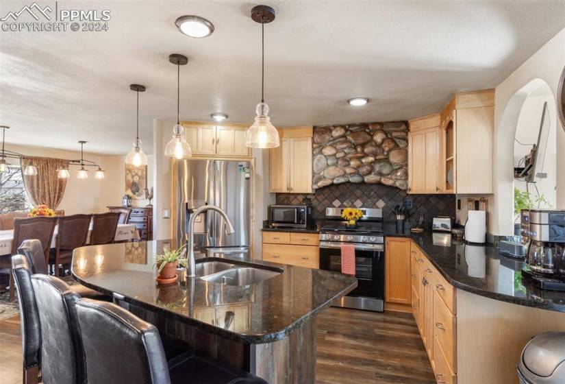 Kitchen featuring tasteful backsplash, appliances with stainless steel finishes, pendant light fixtures