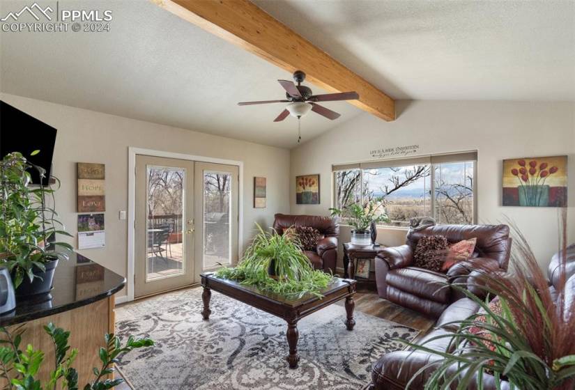 Living room addition featuring french doors, lofted ceiling with natural wood beam, ceiling fan, ample natural light and gorgeous mountain views.