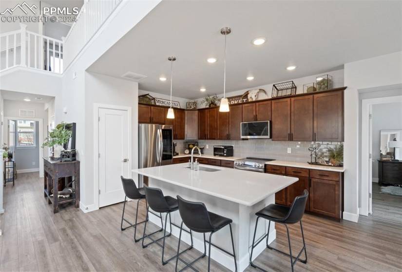 Kitchen with a breakfast bar area, a kitchen island with sink, appliances with stainless steel finishes, and light wood-type flooring