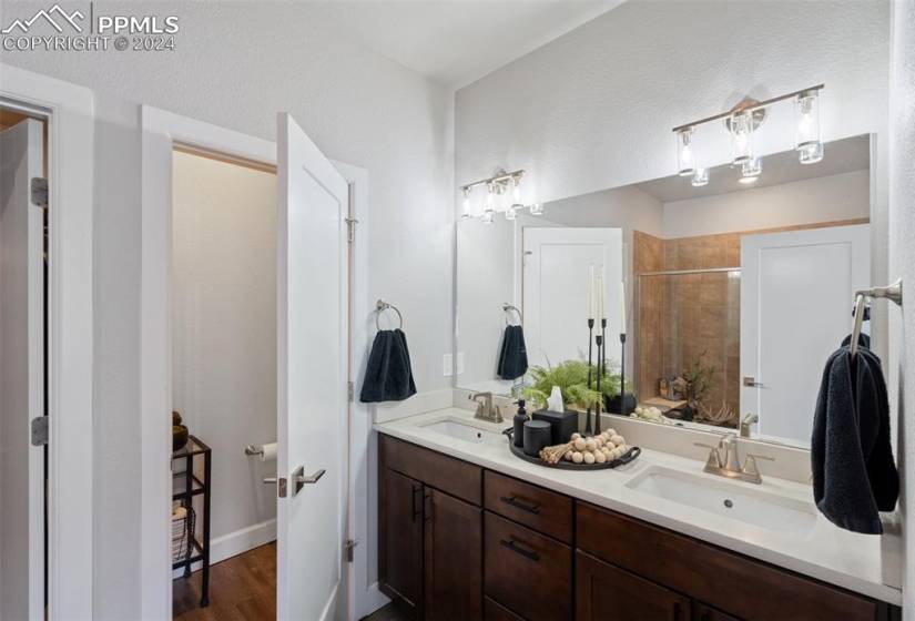Main Level Primary Bathroom featuring vanity with extensive cabinet space, double sink, and wood-type flooring