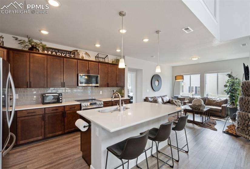 Kitchen featuring a kitchen island with sink, pendant lighting, sink, appliances with stainless steel finishes, and hardwood / wood-style flooring