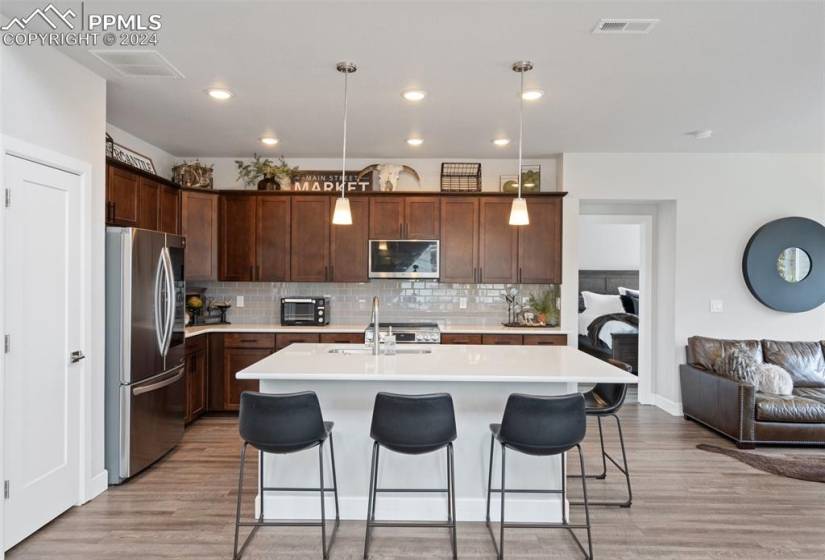 Kitchen featuring a kitchen island with sink, pendant lighting, light hardwood / wood-style floors, and stainless steel appliances