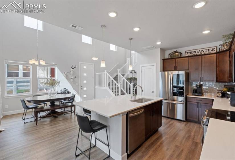 Kitchen featuring a chandelier, hardwood / wood-style floors, a kitchen island with sink, and appliances with stainless steel finishes