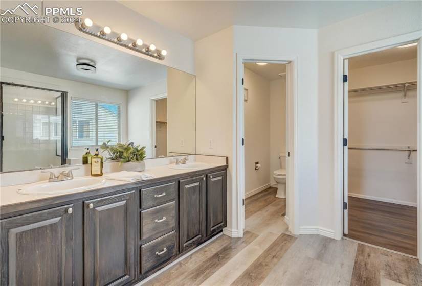 Master Bathroom with double vanity, beautiful flooring and a large walk-in closet