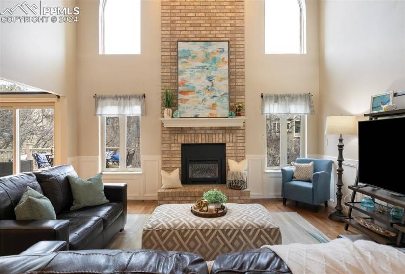 Family room with a brick fireplace, a lots of sunlight, and hardwood floors