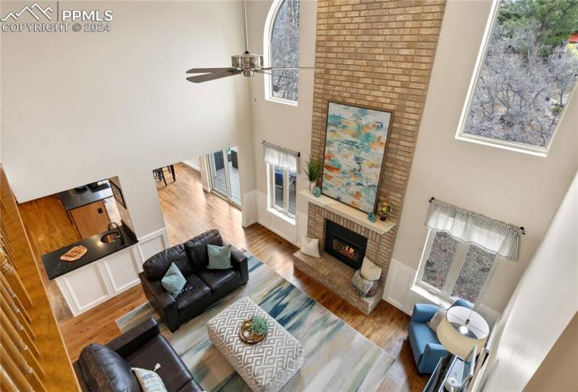 Family room off of kitchen with a high ceiling, ceiling fan, a brick fireplace, and  lots of light